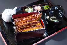 Regular eel served over rice in a lacquered box The size of the eel is a whole tail